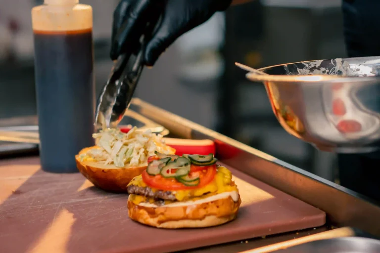 Professional burger preparation demonstrating kitchen essentials training techniques | Préparation professionnelle de burger illustrant les techniques de formation aux bases de cuisine